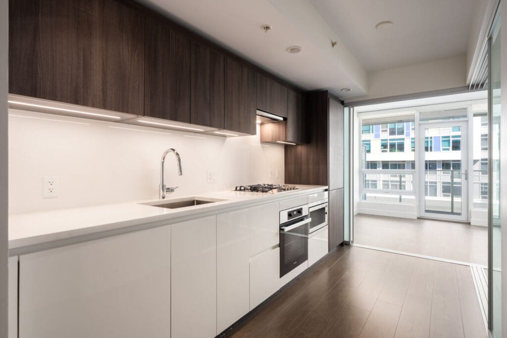 Modern kitchen in Richmond with white and dark cabinets, stainless appliances, gas stove, and large window to city views on No.3 Rd.