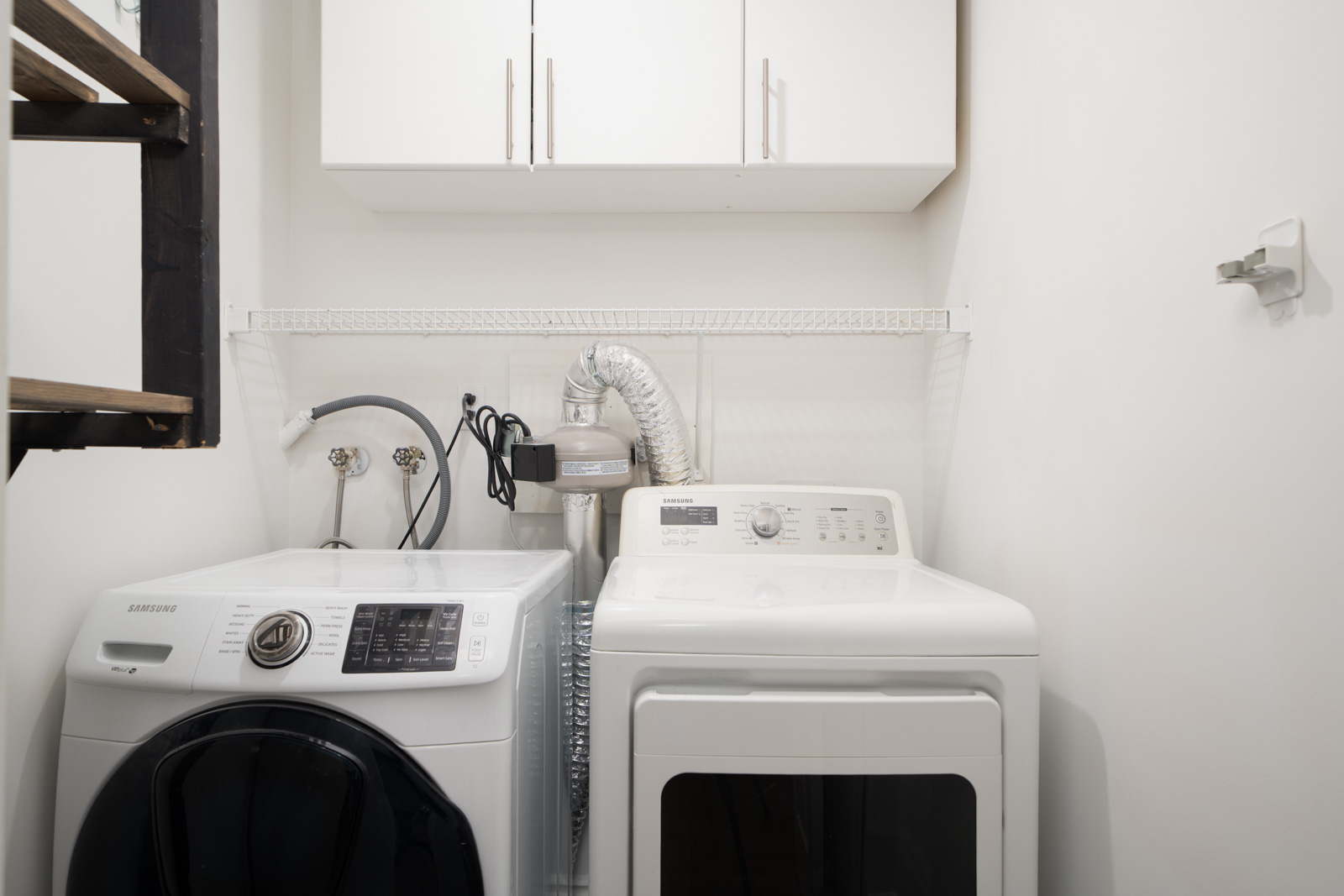 Laundry room at 1245 Quayside Dr, New Westminster with washer and dryer side by side, cabinet above, and shelf behind.