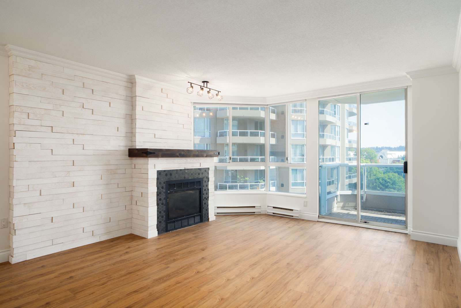 Unfurnished living room with wood floors, fireplace, large windows, and a balcony on Quayside Dr in New Westminster. 12th floor view.