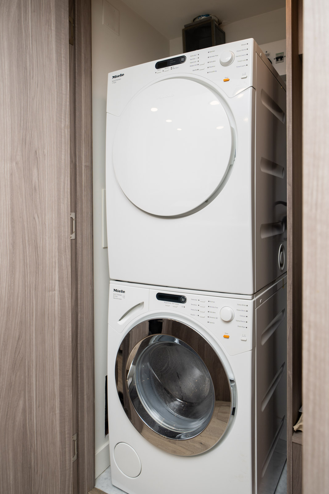 Stacked front-loading washer and dryer inside a wooden closet in a SW Marine Dr, Vancouver home.