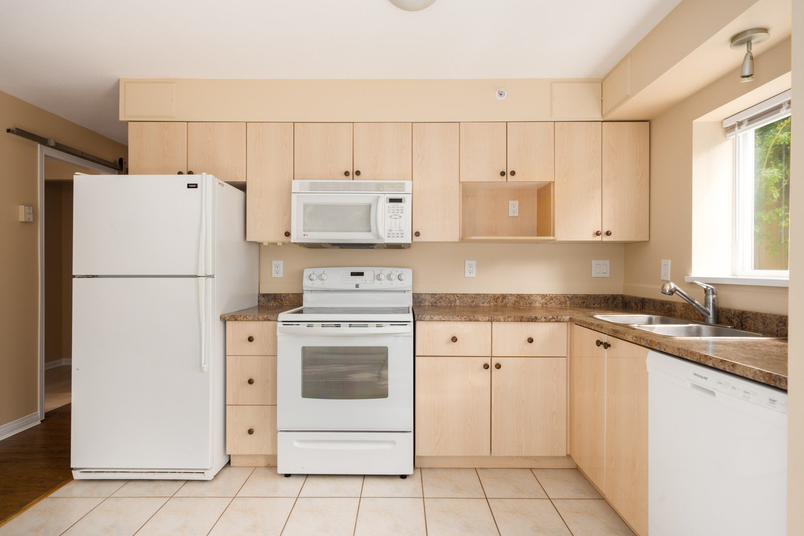 Modern kitchen on 1st floor at 1099 West 71st Ave, Vancouver, with light wood cabinets, white appliances, and tiled floor.