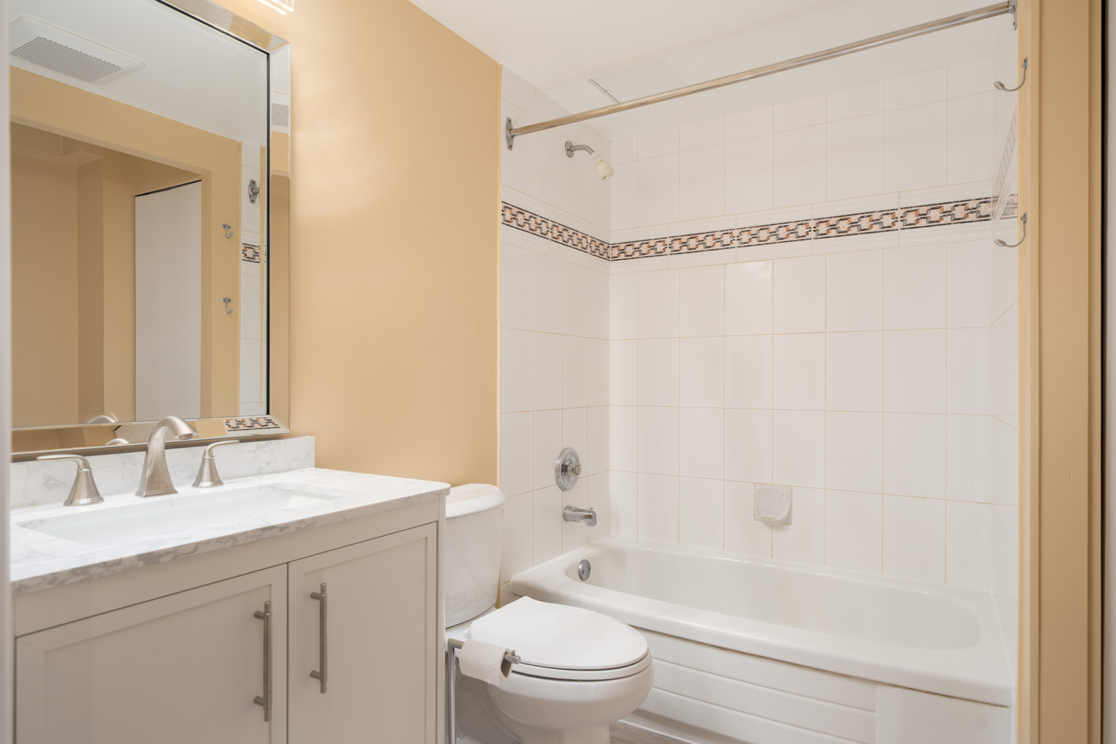 First-floor bathroom at 1099 West 71st Ave, Vancouver with beige walls, white vanity, marble countertop, mirror, toilet, and bathtub.