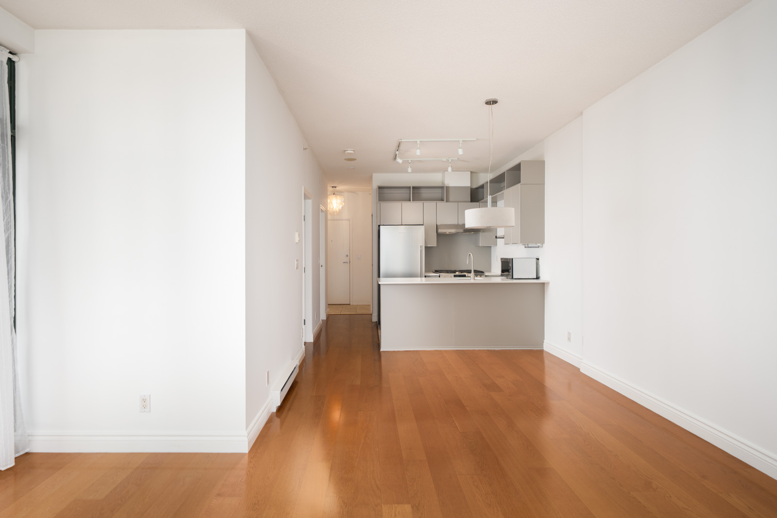 Unfurnished modern apartment at 1239 W Georgia St, Vancouver, with wood floors, white walls, open kitchen, and natural light.