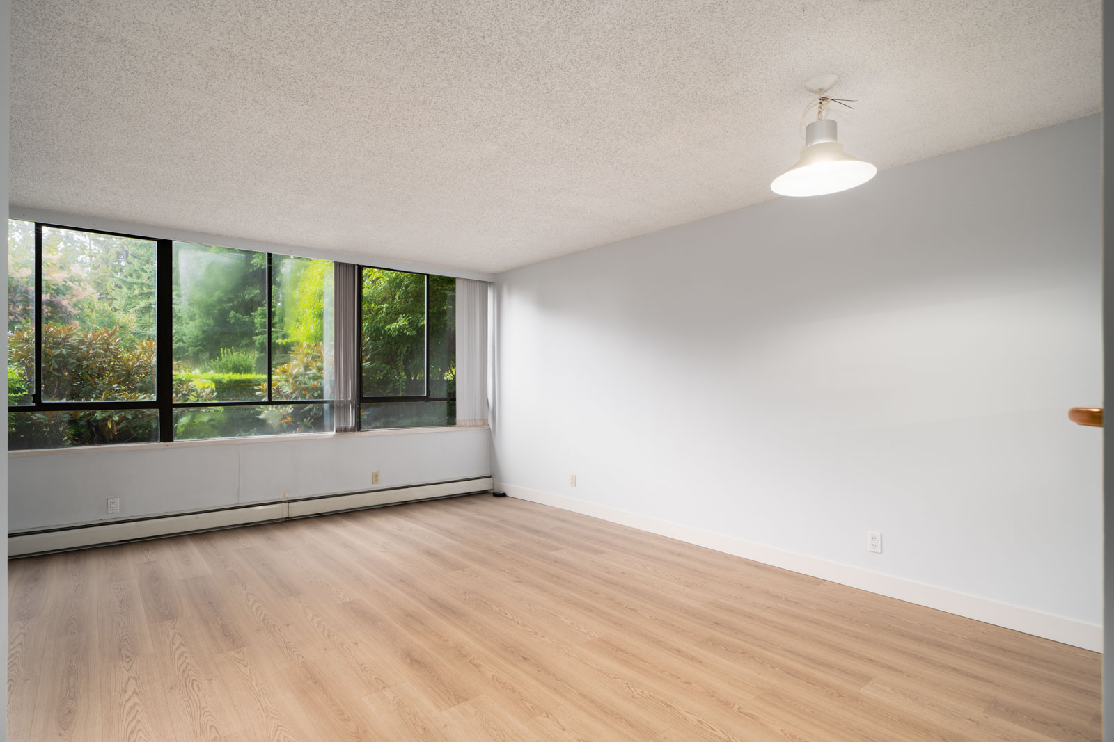 Unfurnished room in 1st floor condo at 460 Westview St, Coquitlam, with large windows, light wood floors, and white walls.