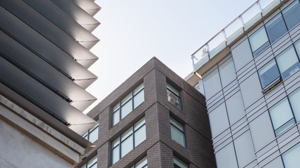 Upward view of three modern condo buildings in Greater Vancouver BC presented by property management company Birds Nest Properties