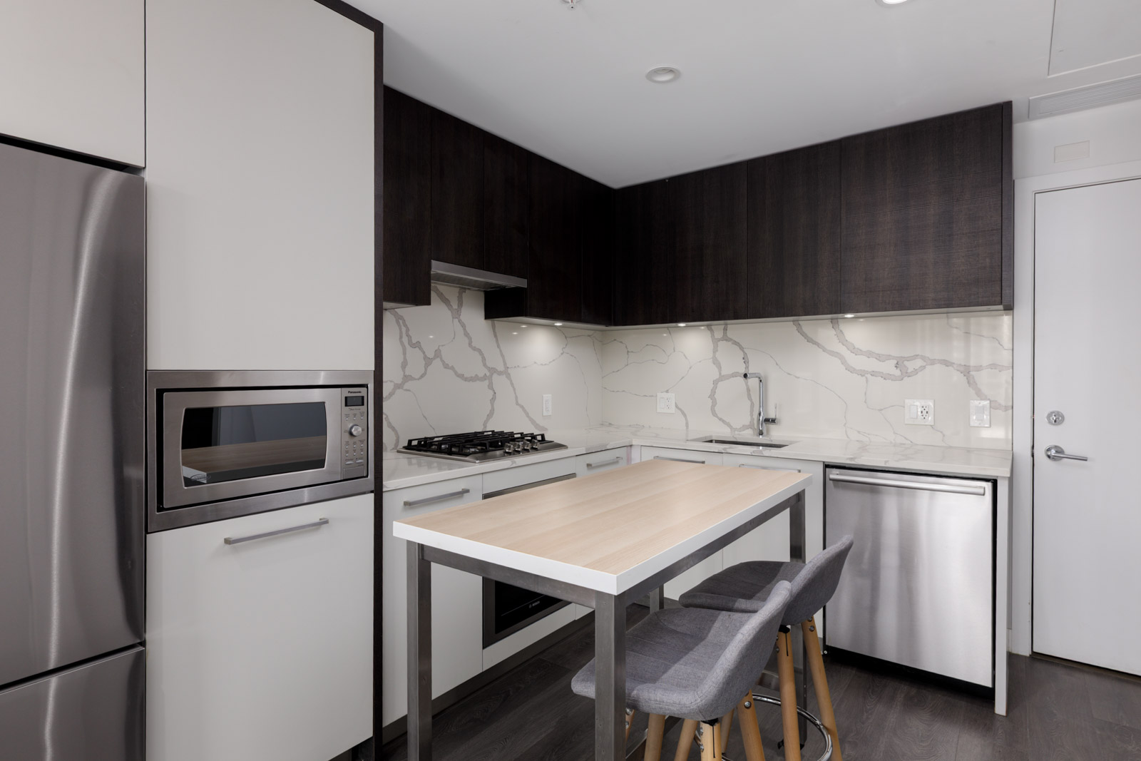 Modern kitchen at 567 Clarke Rd, Coquitlam with two-tone cabinets, marble backsplash, stainless appliances, and wood island with stools.