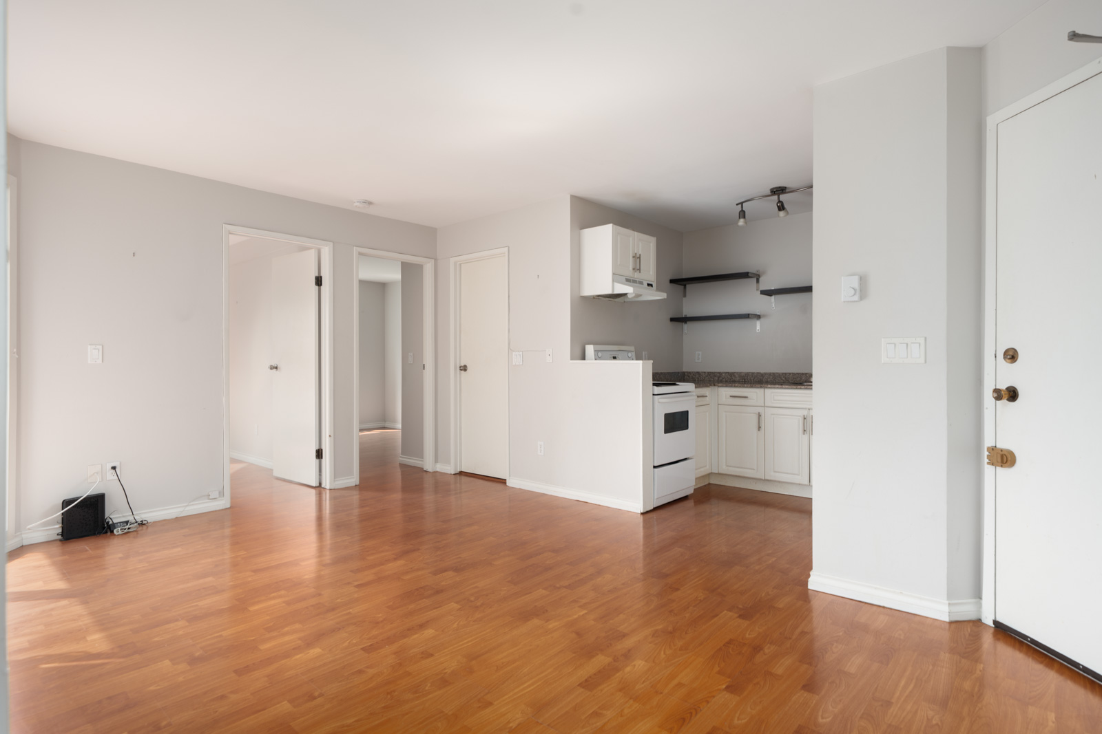 Unfurnished Vancouver apartment at 2365 W 5th Ave with light wood floors, white walls, small kitchen, and natural light from the left.
