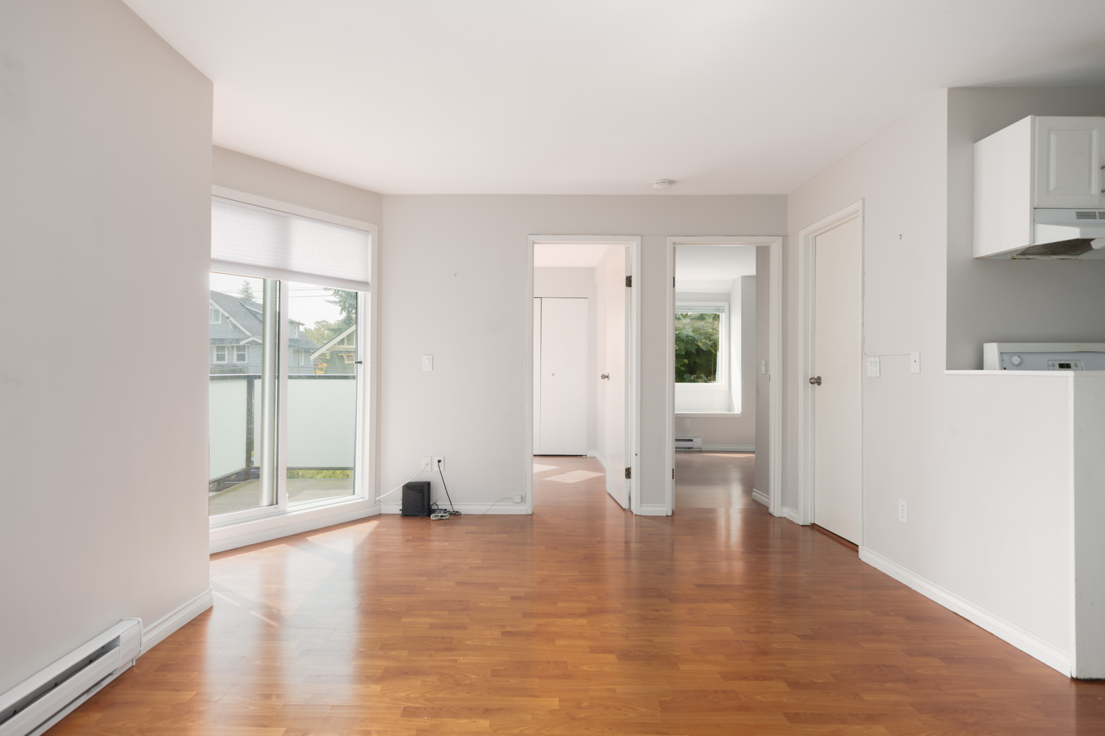 Bright, empty 2nd-floor apartment on West 5th Avenue, Vancouver, with light walls, wood floors, big window, and balcony door.
