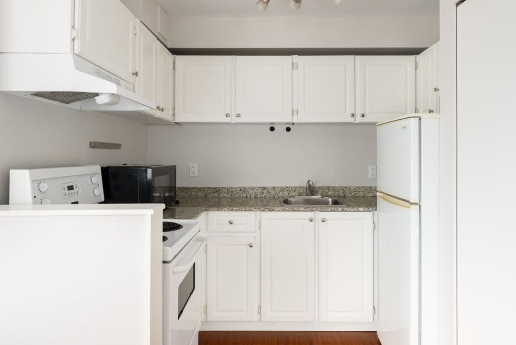 Small kitchen on 3rd floor at 2365 West 5th Ave, Vancouver, with white cabinets, appliances, granite countertop, and bright lighting.