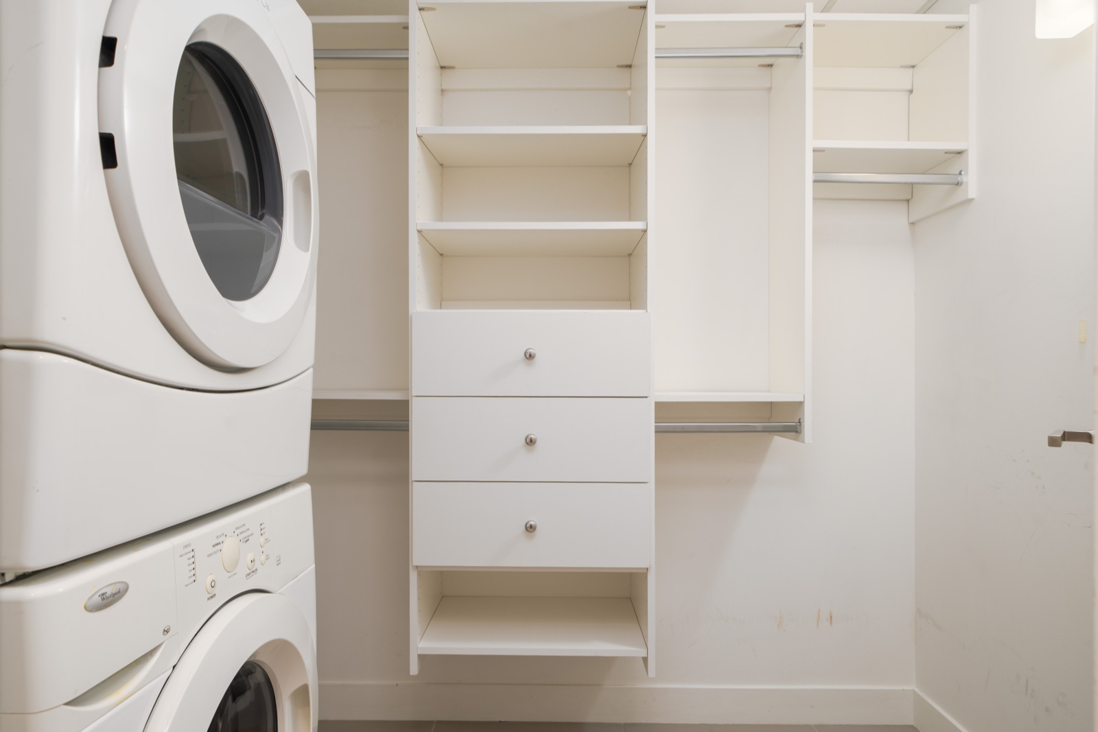 Stacked washer and dryer beside white built-ins in a bright laundry room, townhouse residence at 108 E 1st Ave, Vancouver.