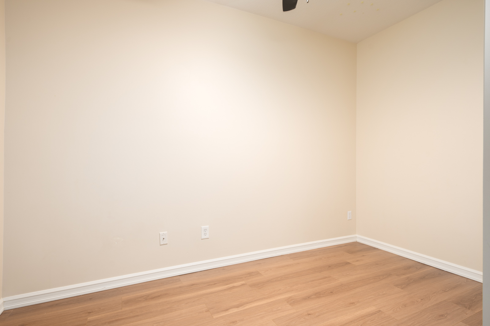 Empty room in Surrey at 10088, 148 Street, with beige walls, light wood floors, white baseboards, outlets, and ceiling vent.
