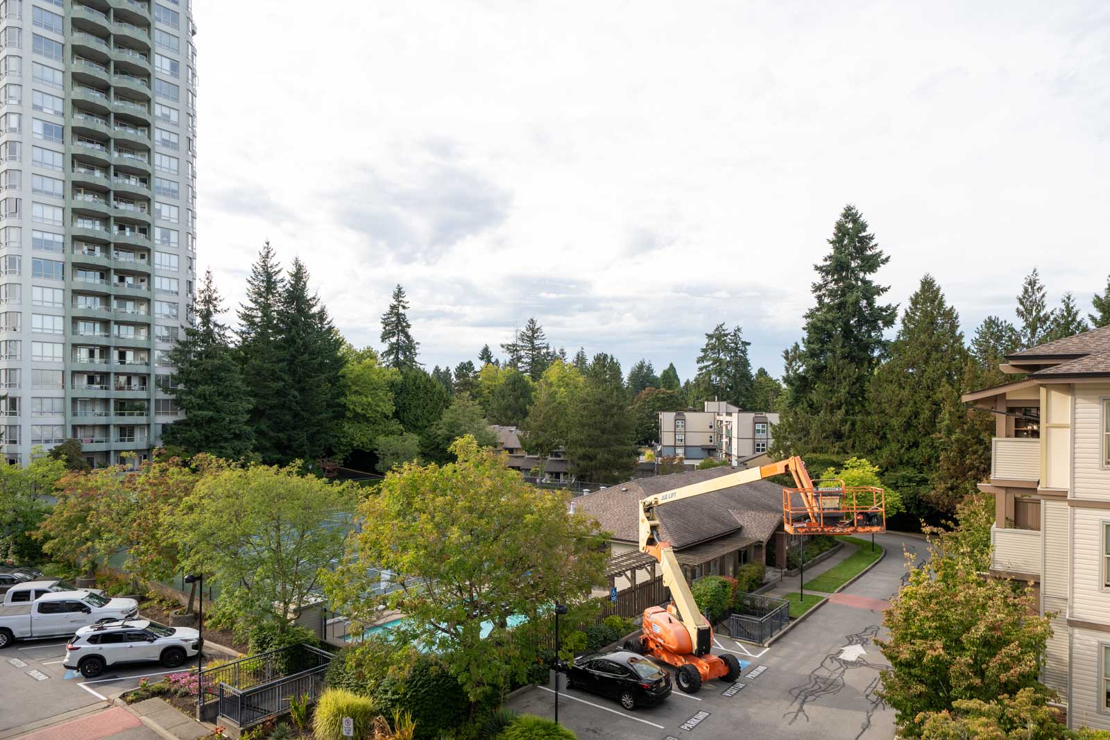 A construction lift with workers is raised to the 4th floor of a building on 148 Street in Surrey; cars, trees, and an apartment tower are nearby.