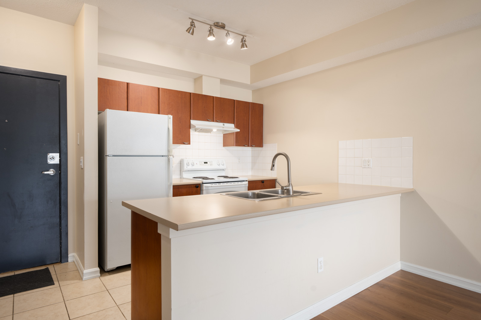 Modern kitchen at 10088, 148 St, Surrey with stainless fridge, white stove, brown cabinets, beige counters, and island sink.