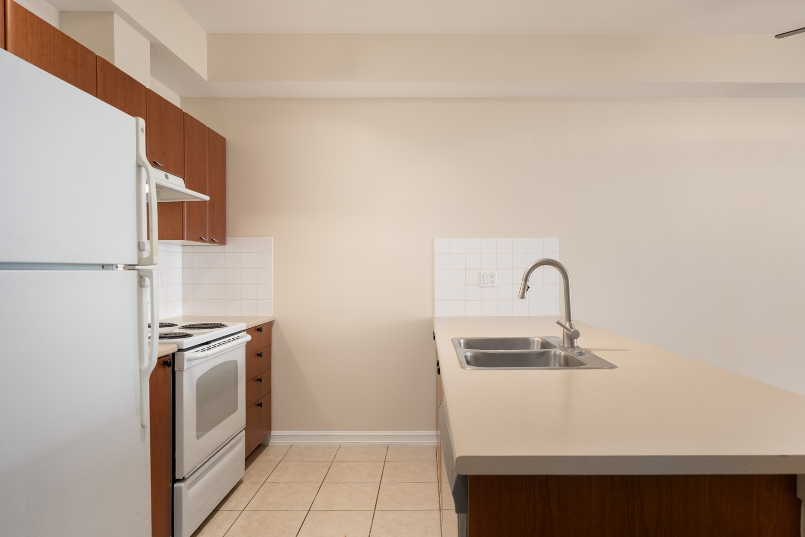 Surrey kitchen on 148 Street with white appliances, wooden cabinets, tile backsplash, beige counters, and tiled floors at 10088.