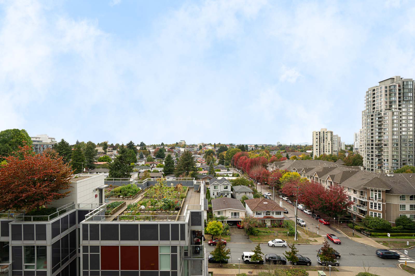 Residential neighborhood on Boundary Rd, Vancouver, with tree-lined streets, apartments, and rooftop gardens under cloudy skies.