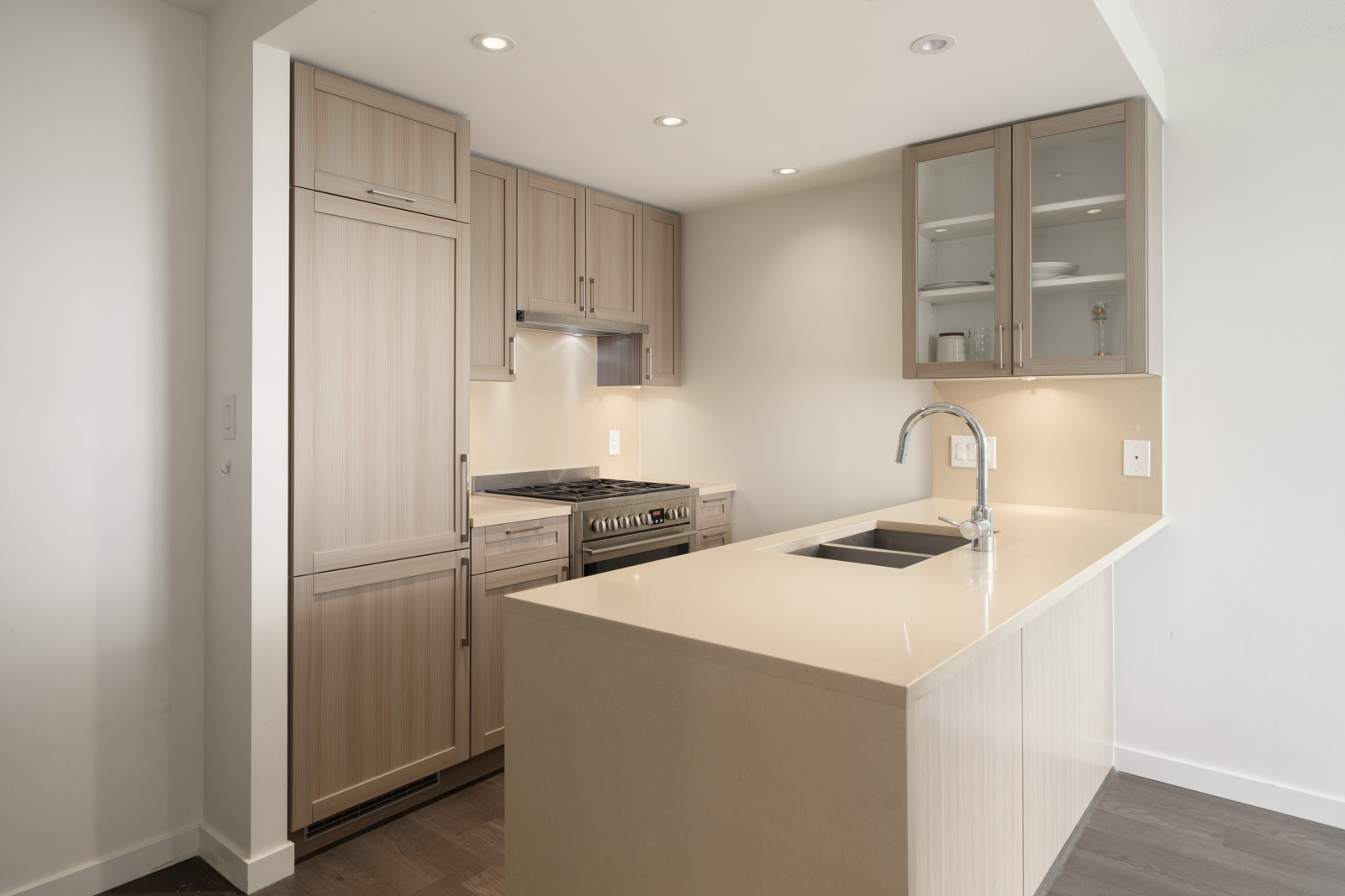 Modern kitchen on Boundary Rd Vancouver with light wood cabinets, glass-door shelves, gas stove, dishwasher, and large island sink.