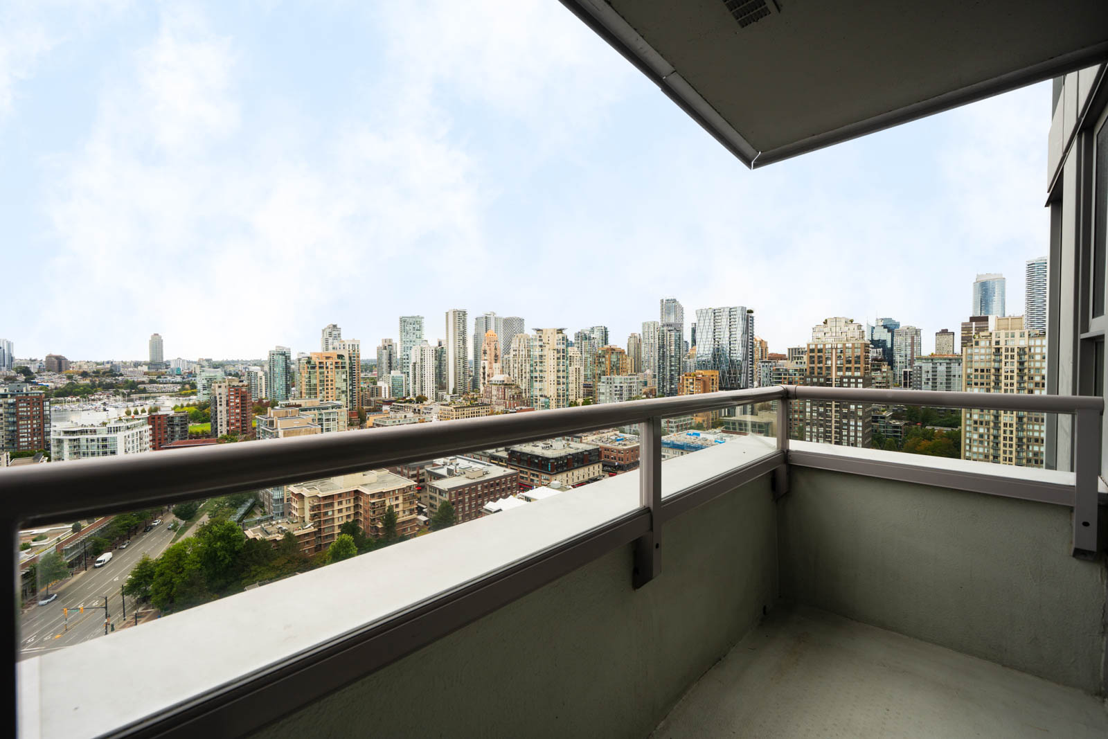 View from a high-rise balcony at 1008 Cambie St, showing Vancouver’s skyline with many tall buildings under a partly cloudy sky.