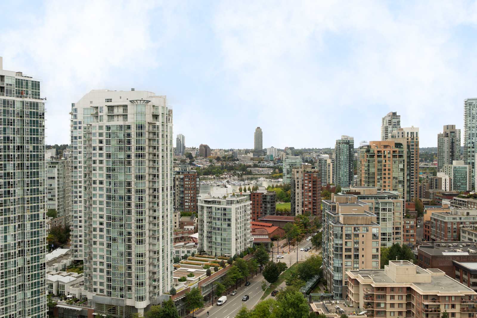 Vancouver high-rise buildings with roads, trees, and a partly cloudy sky seen from the 29th floor near Cambie St.