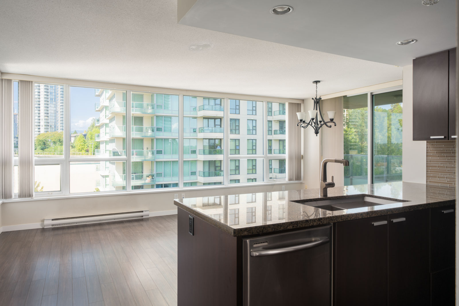 Unfurnished modern apartment with large windows, dark kitchen, granite counters, and city views at 2232 Douglas Rd, Vancouver.