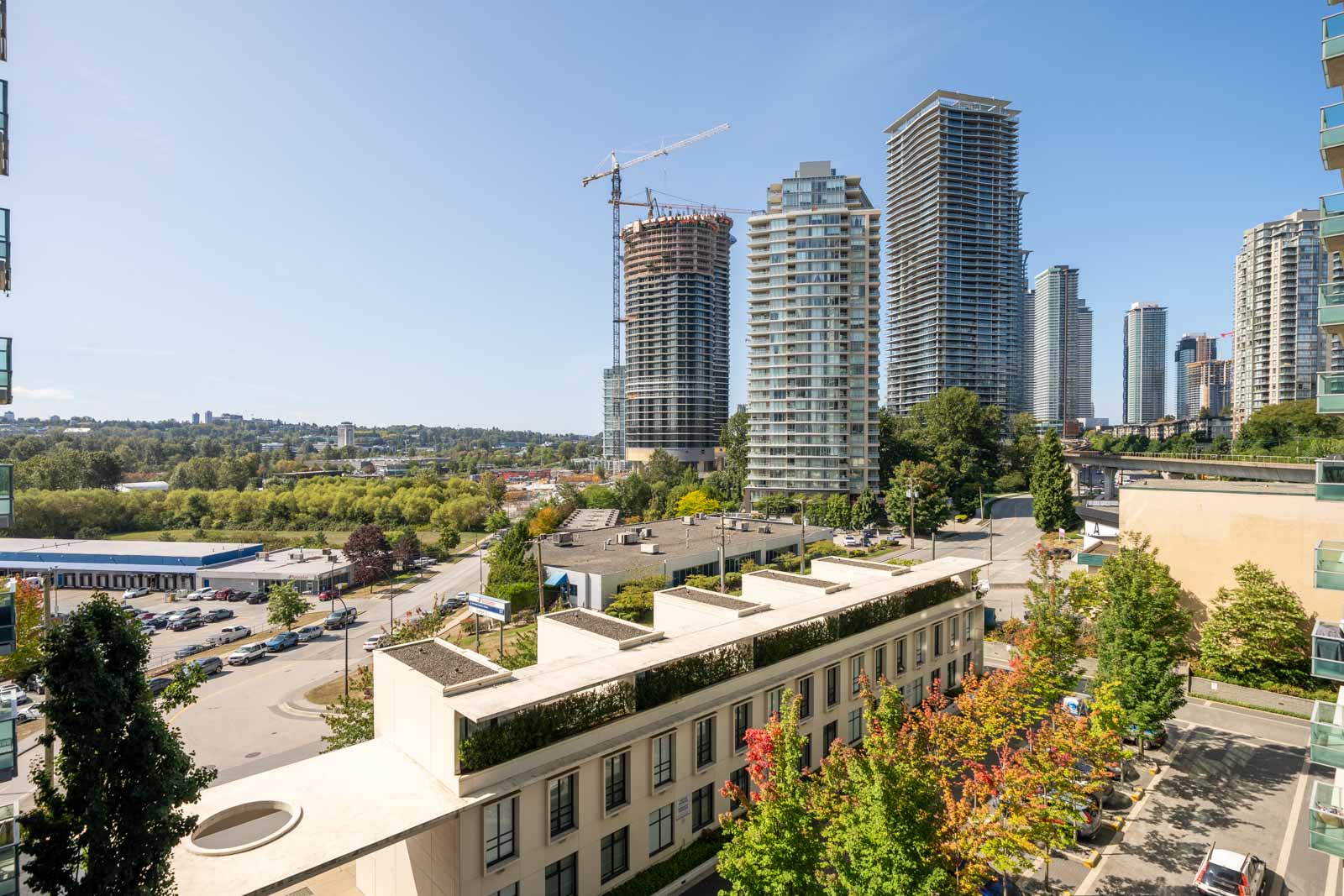 Cityscape of high-rises near Douglas Rd, Vancouver, including 2232 Douglas Rd, with a crane and trees under a blue sky.