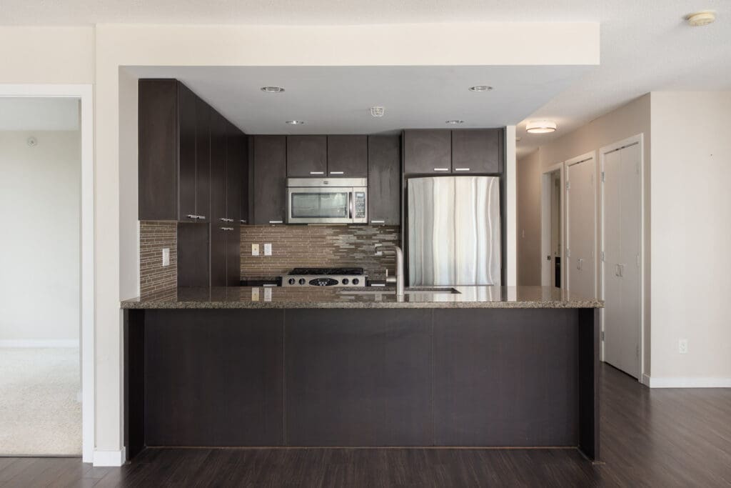 Modern kitchen with dark cabinets, stainless steel appliances, granite counters, and tile backsplash in a 7th floor Vancouver home.