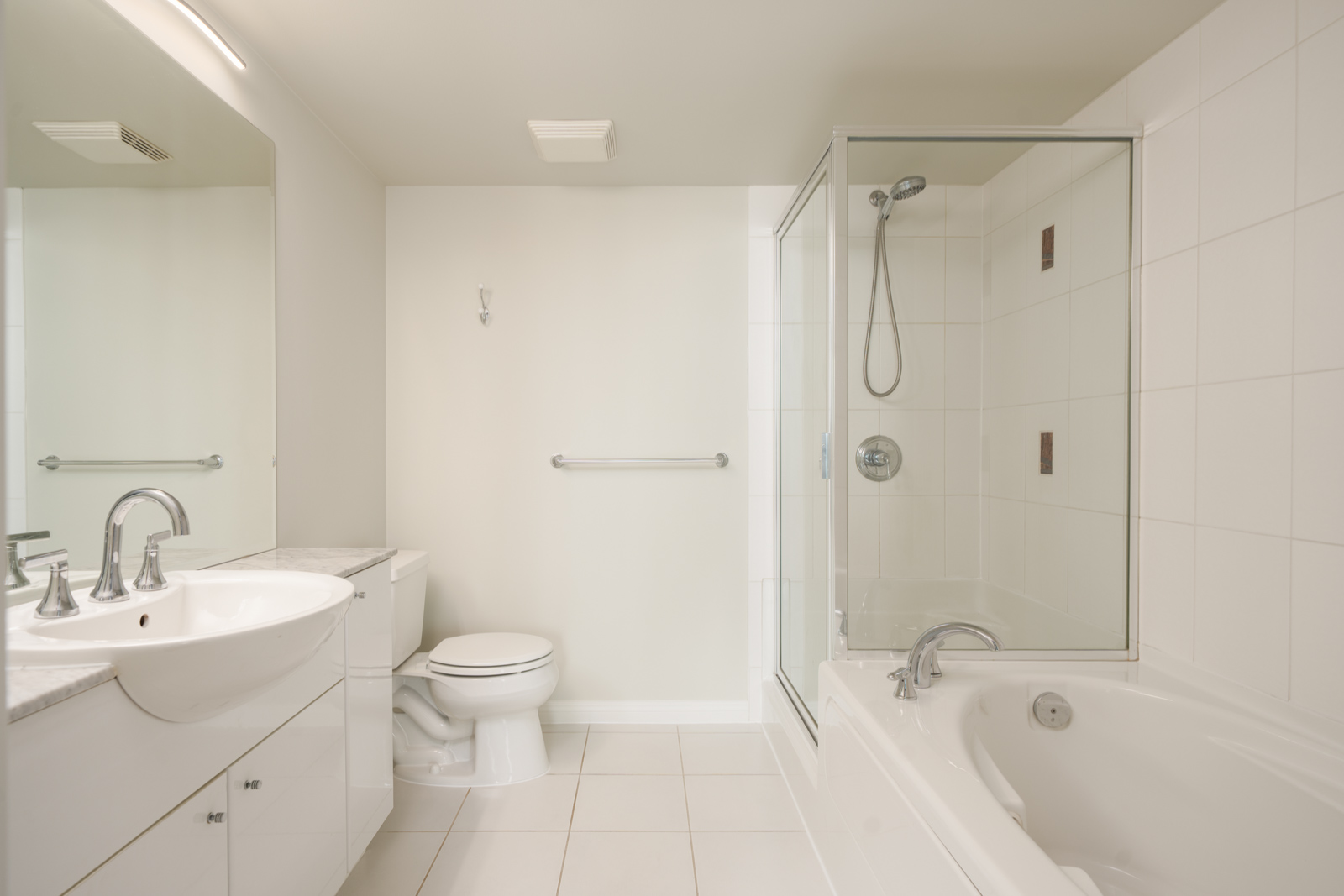 Modern bathroom on the 12th floor at 188 E Esplanade, North Vancouver, with white tile, glass shower, tub, and chrome fixtures.