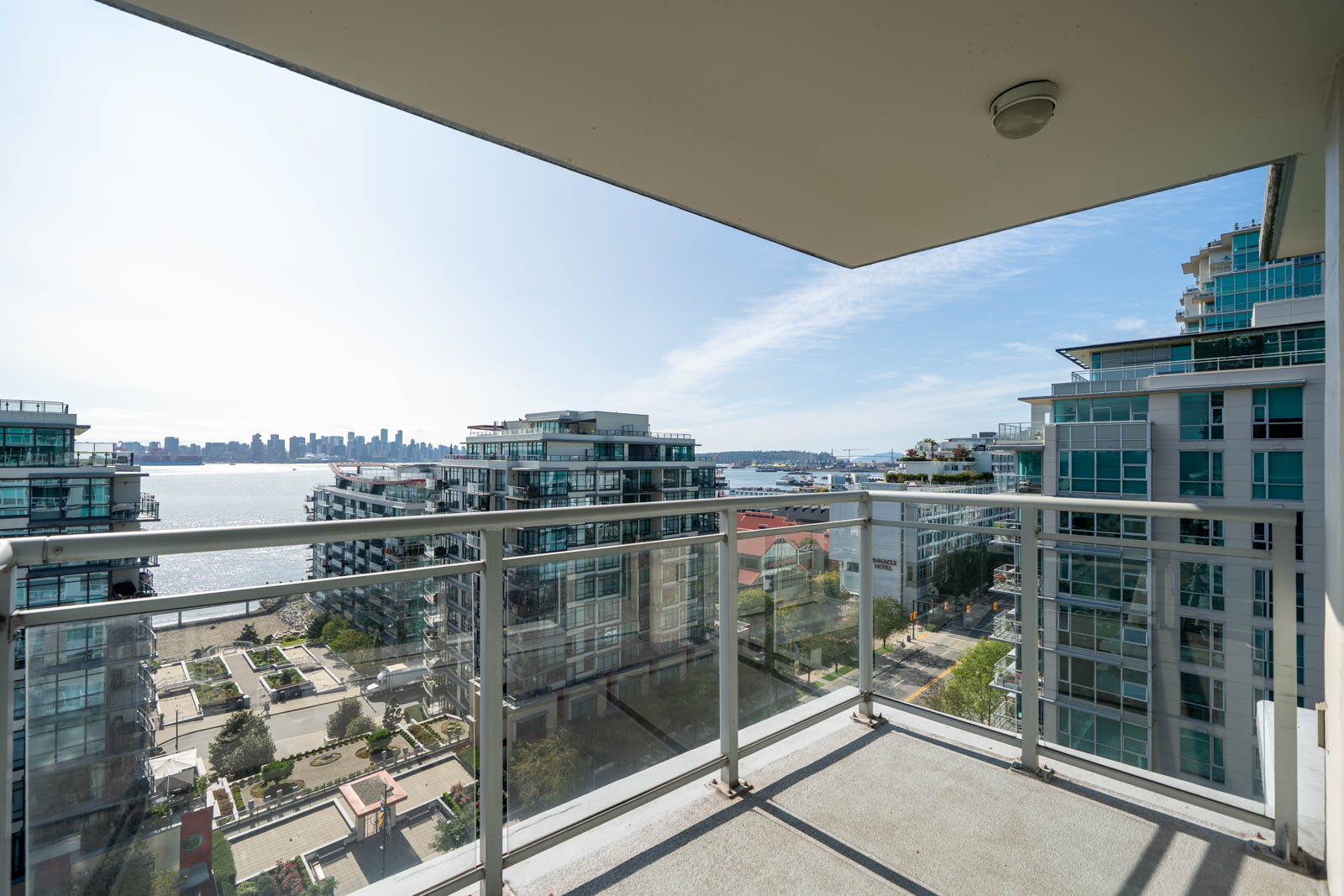 High-rise balcony view at 188 E Esplanade, North Vancouver, showing apartments, waterfront, and distant skyline under clear skies.
