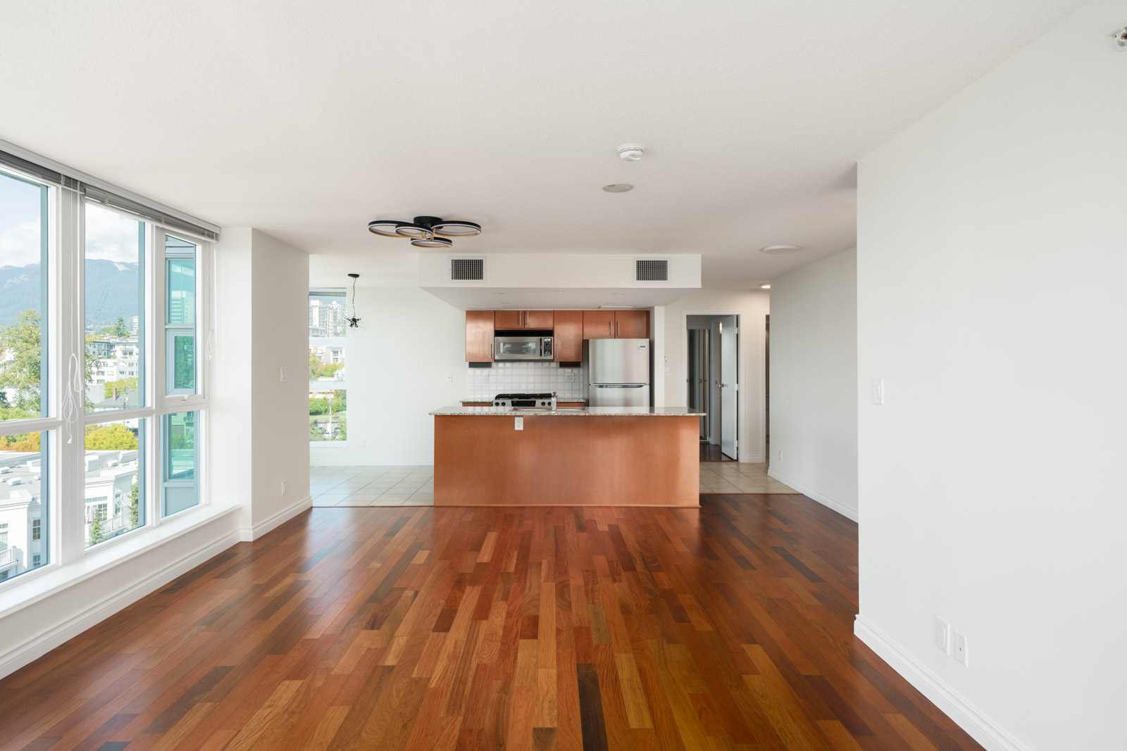 Unfurnished apartment at 188 E Esplanade, North Vancouver, with wood floors, large windows, open kitchen, and 12th-floor views.