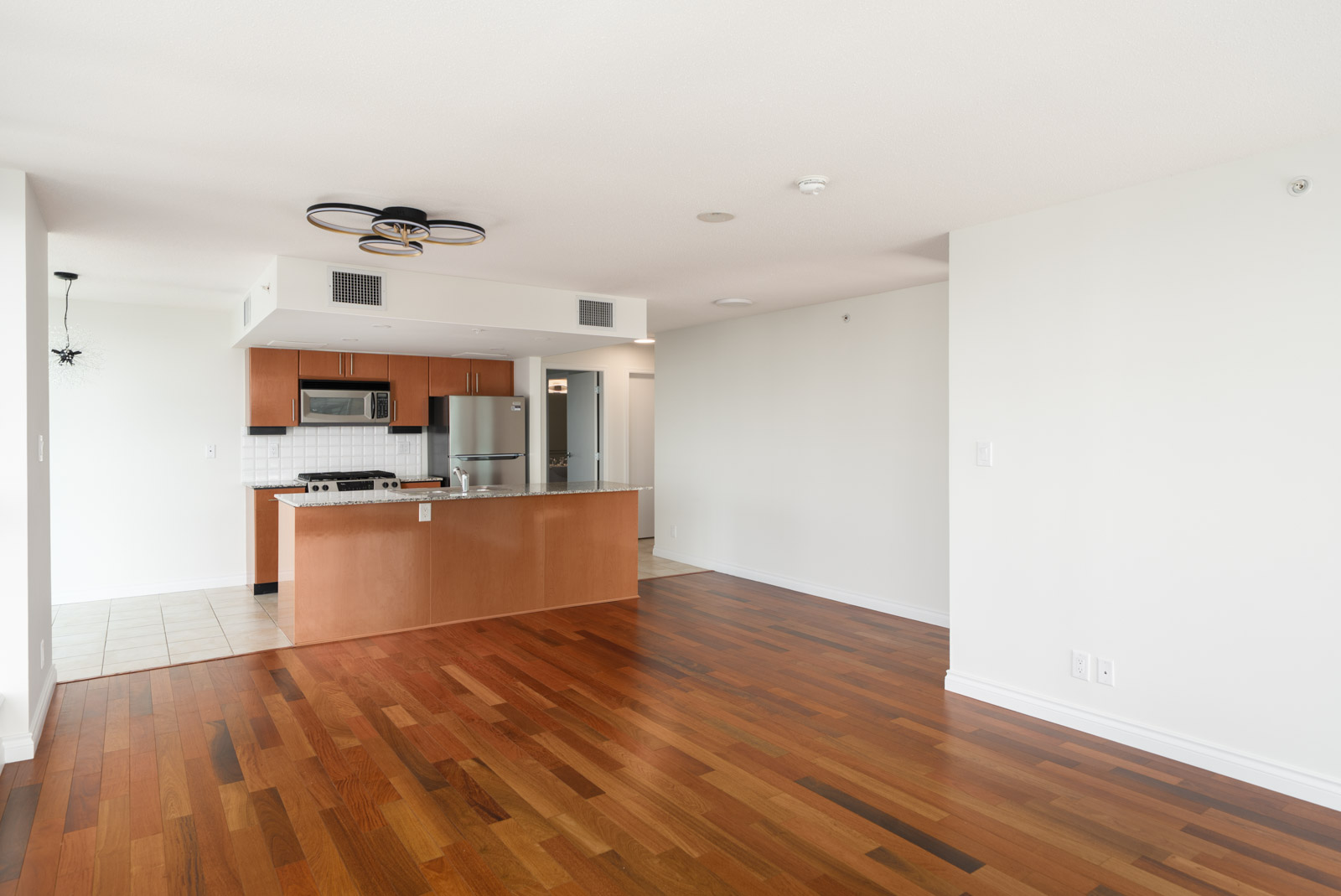 Unfurnished 12th-floor North Vancouver apartment with wood floors, open layout, modern kitchen, and minimal lighting.