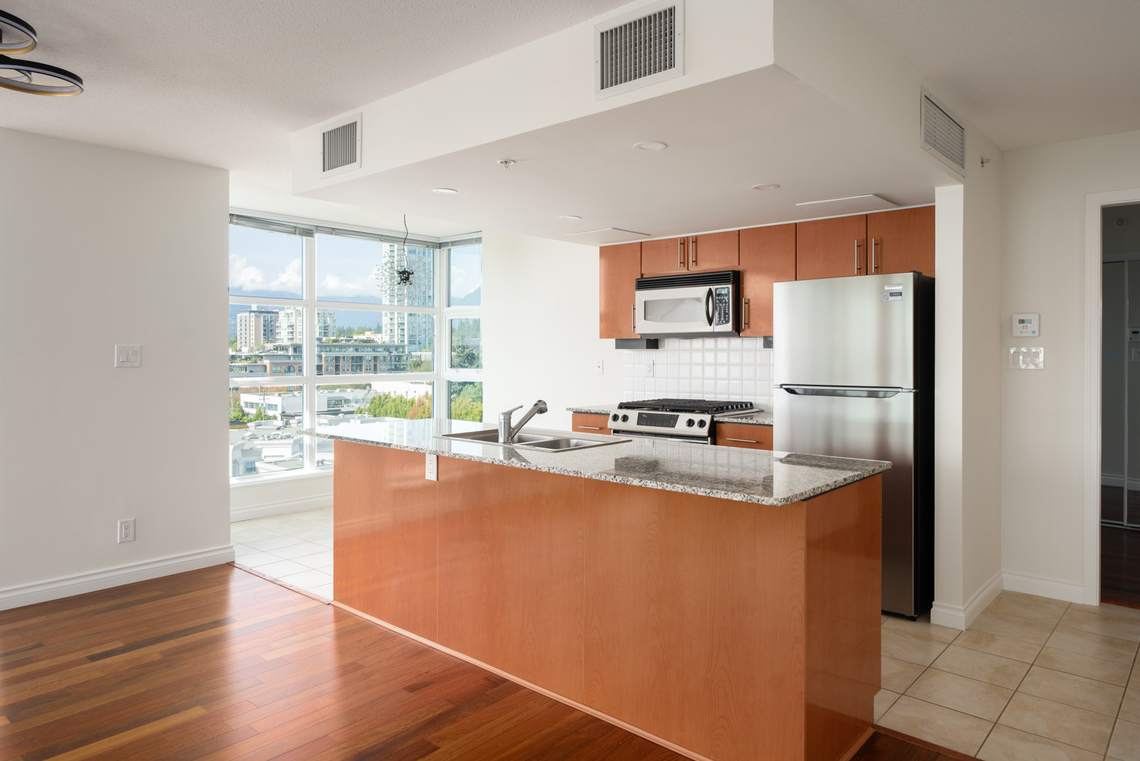 Modern kitchen with wood cabinets, stainless steel appliances, granite countertops, and large windows on E Esplanade, North Vancouver.