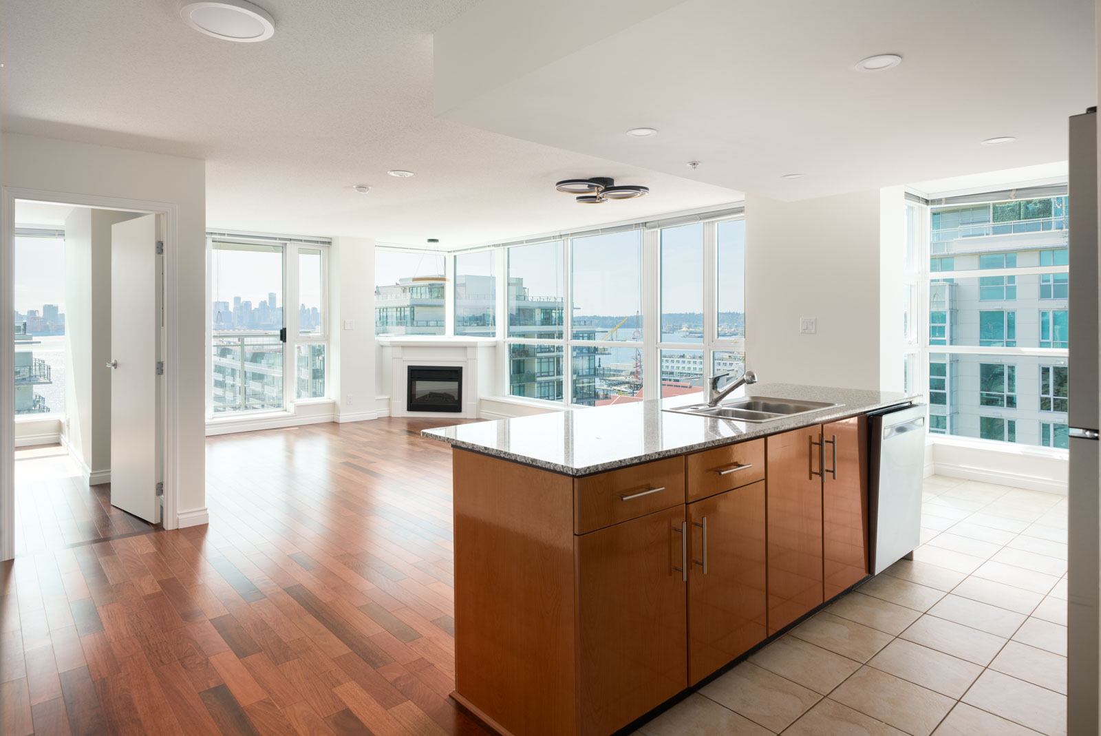 12th-floor apartment at 188 E Esplanade, North Vancouver; open kitchen, wood floors, large windows with city and water views.