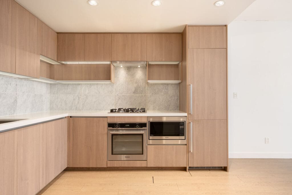 Modern kitchen at 6538 Nelson Ave, Burnaby with light wood cabinets, built-in oven, gas stove, and marble backsplash.