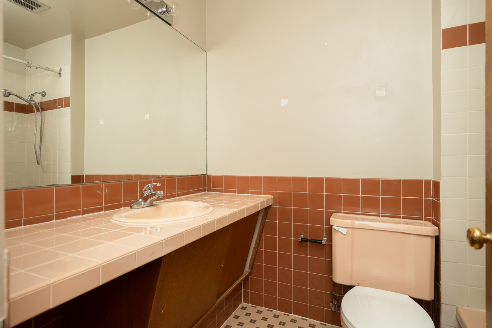 Bathroom with pink sink and toilet, brown tile countertop, wall mirror, and shower; 1st floor, 1970 W 41st Ave, Vancouver.