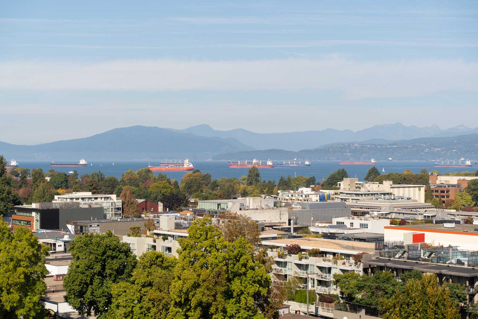 Vancouver city skyline with ships on blue water and mountains beyond, viewed from the 11th floor at 1565 West 6th Avenue.