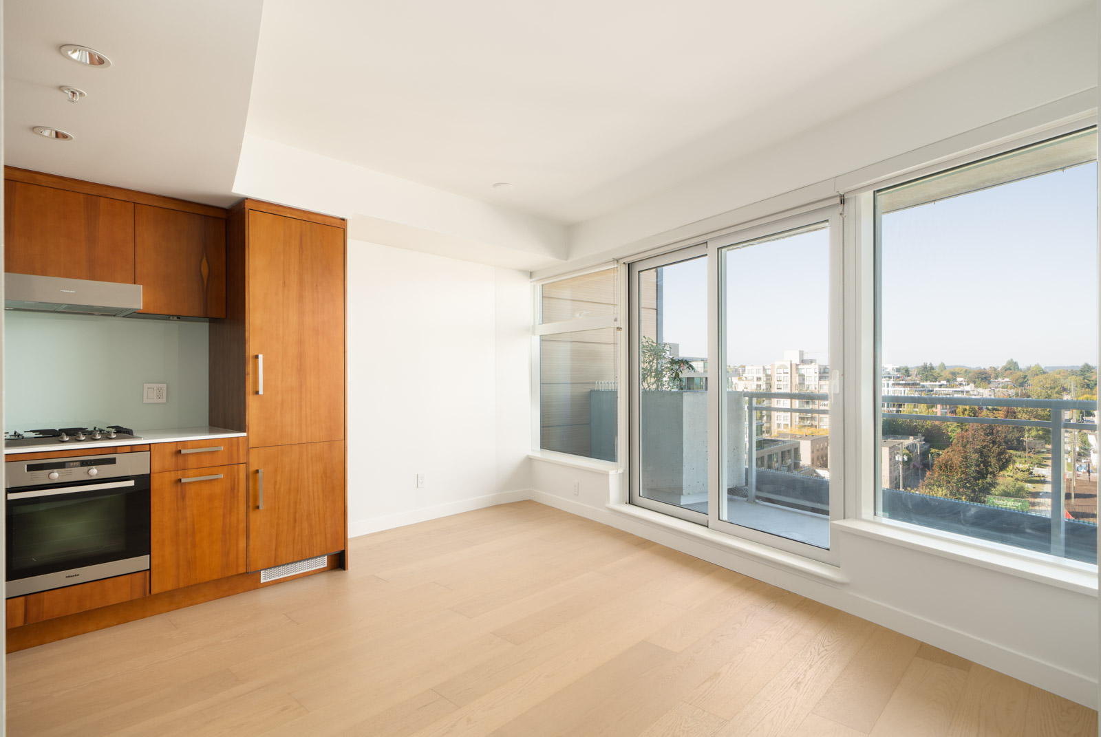 Modern apartment at 1565 West 6th Avenue, Vancouver, with light wood floors, wood cabinets, built-in appliances, and balcony city view.