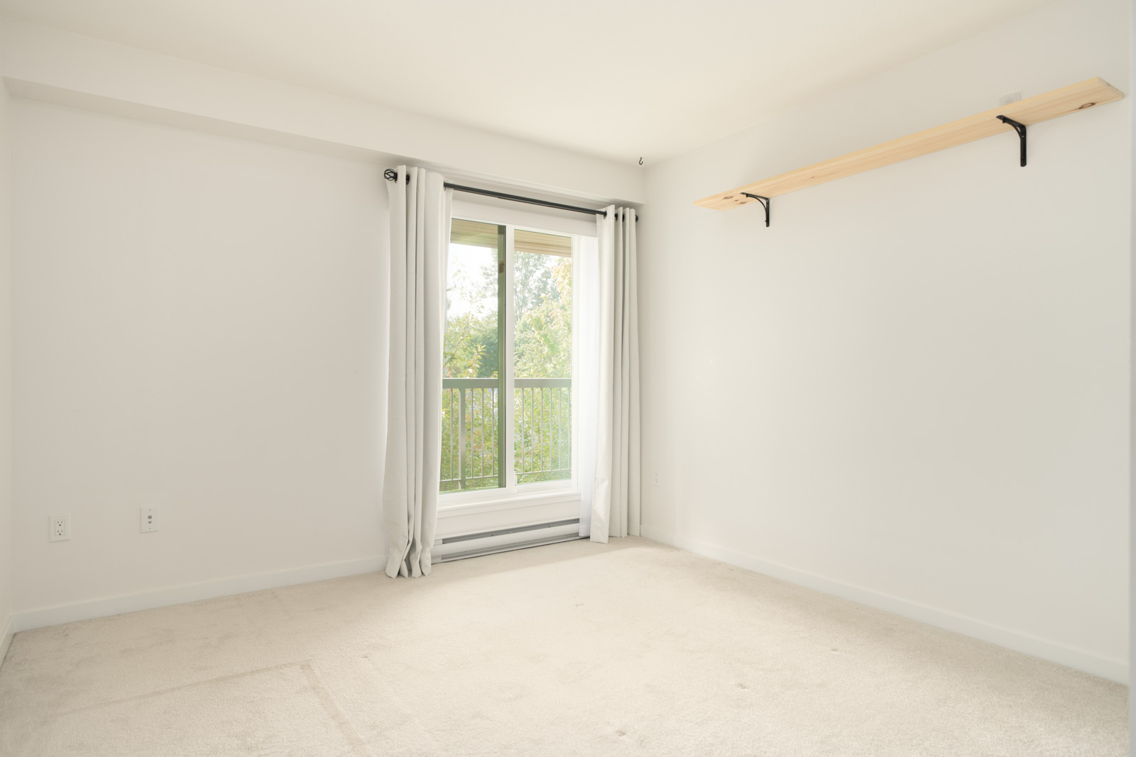 Bright, empty room on the 3rd floor at 2245 Wilson Ave, Port Coquitlam with light carpet, white walls, window and wooden shelf.