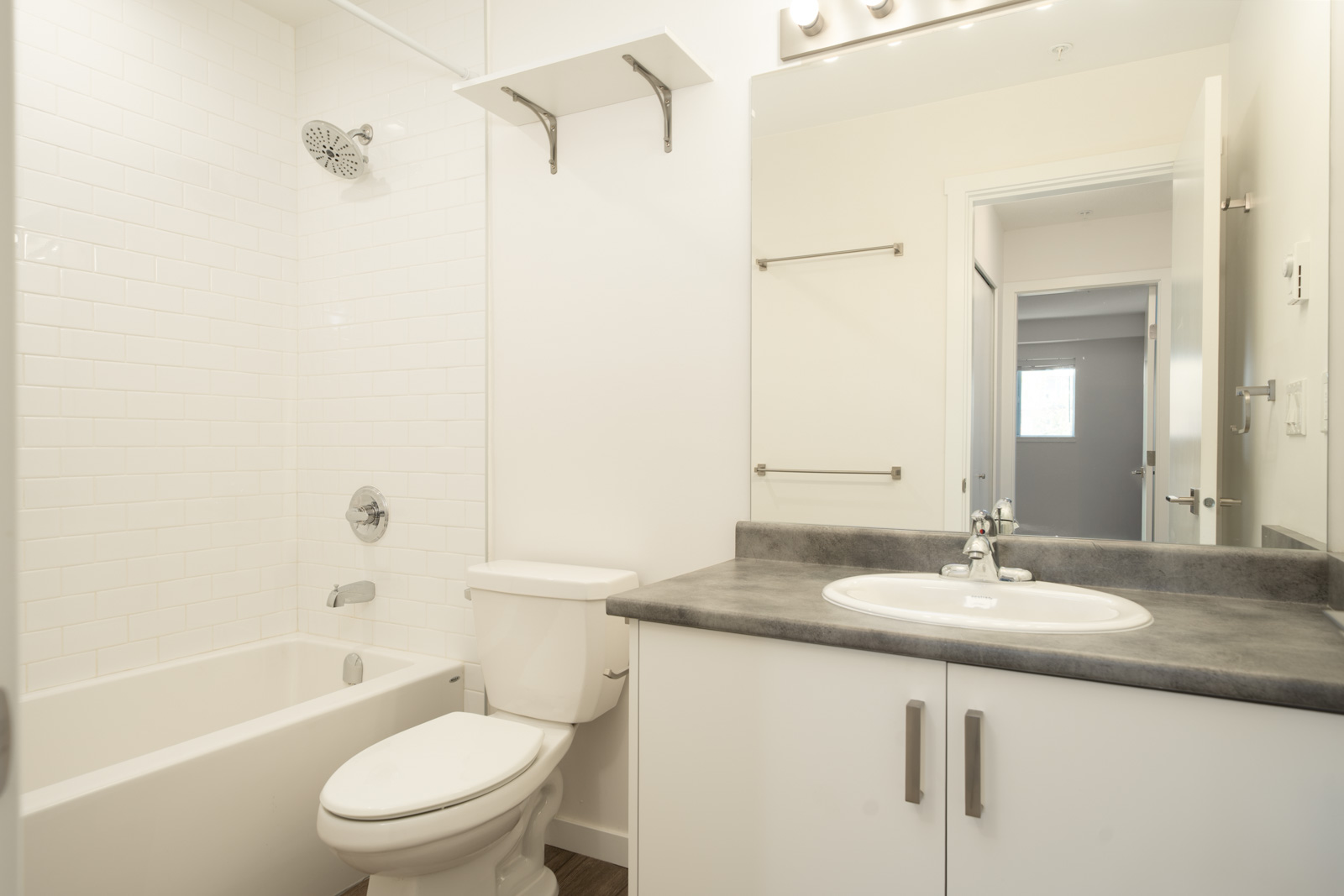 Modern bathroom on 3rd floor, 2245 Wilson Ave, Port Coquitlam, with bathtub/shower, toilet, sink with grey countertop, and white cabinets.