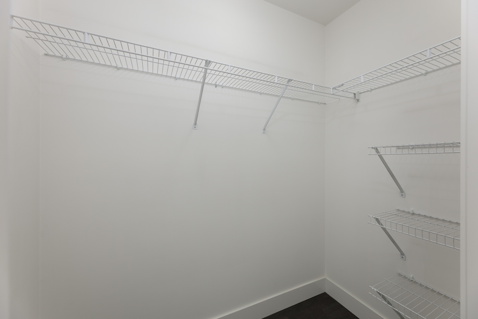 Empty walk-in closet with white walls, black floor, and metal wire shelves on both sides, 4th Floor, 1628 W 4th Ave, Vancouver.