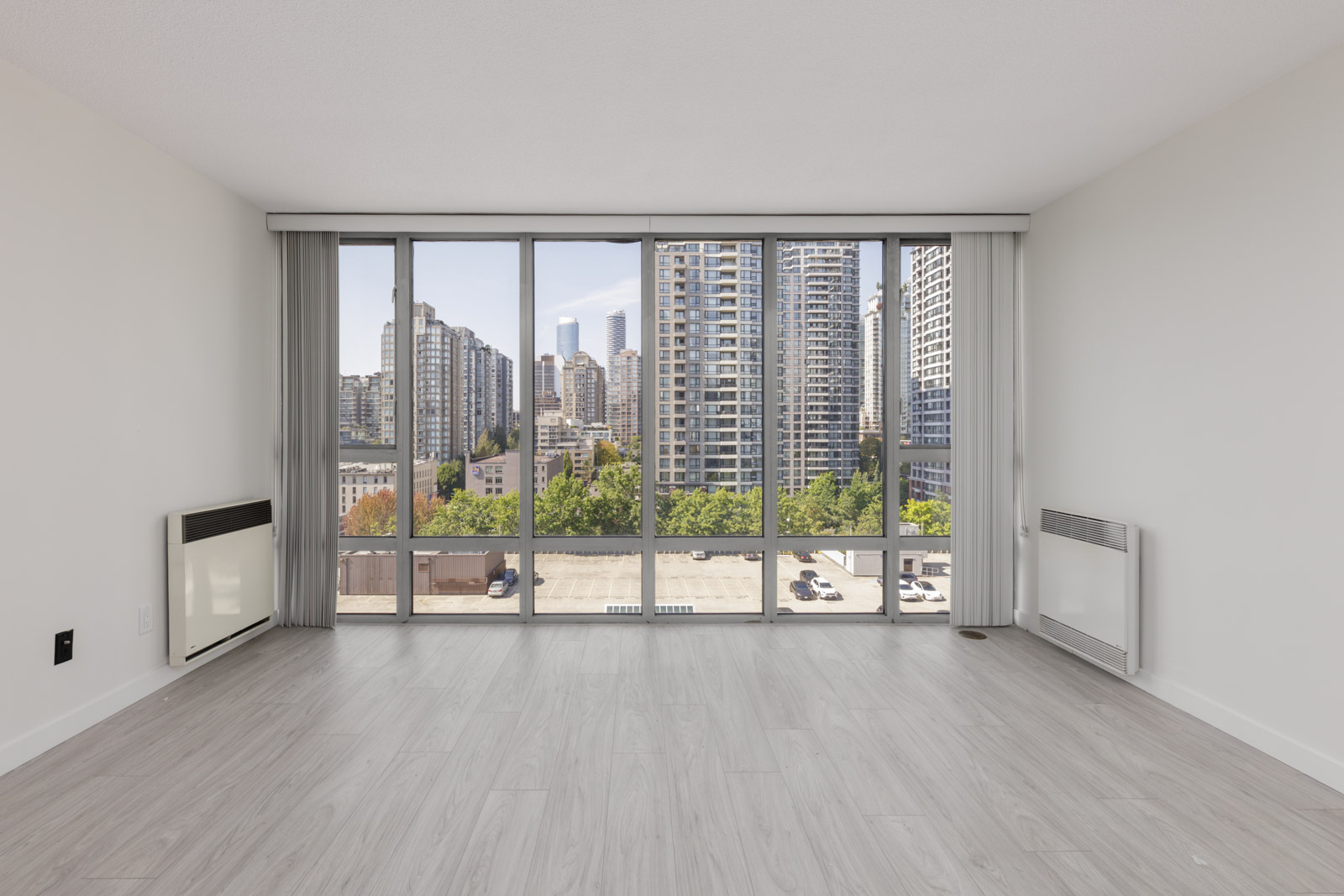 Unfurnished apartment room at 950 Cambie St, Vancouver, with large windows, light wood floors, and cityscape plus parking lot views.