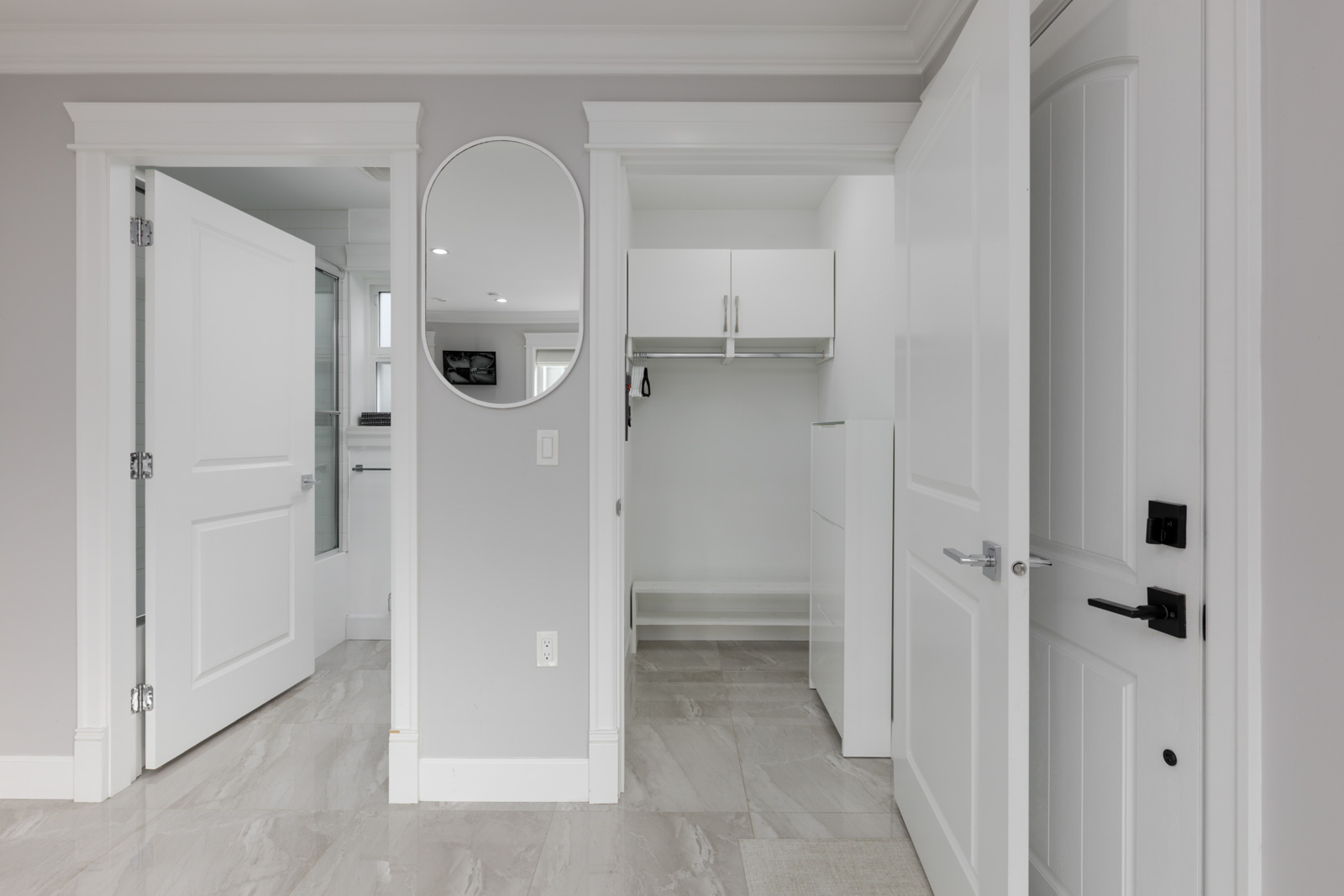 Gray and white room with tile floor, open closet, two open doors, and round mirror in Vancouver’s Falaise Place.
