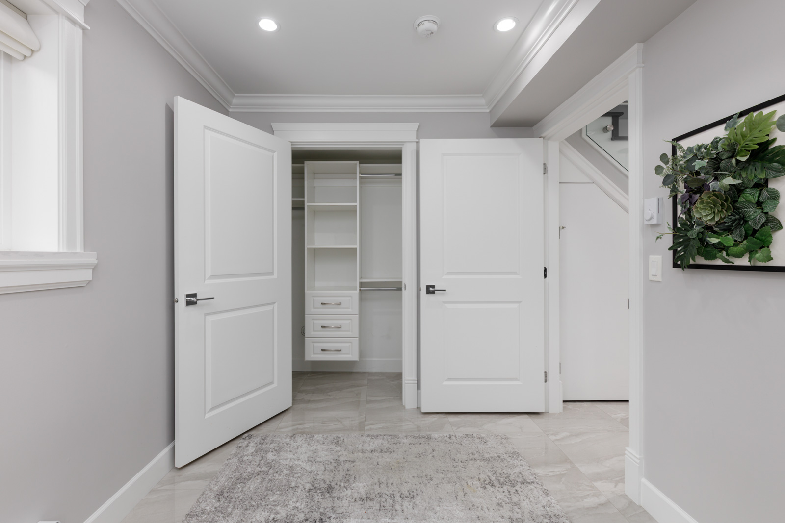 Room at Falaise Place in Vancouver with light gray walls, two open white doors, a built-in closet, and framed plant art.