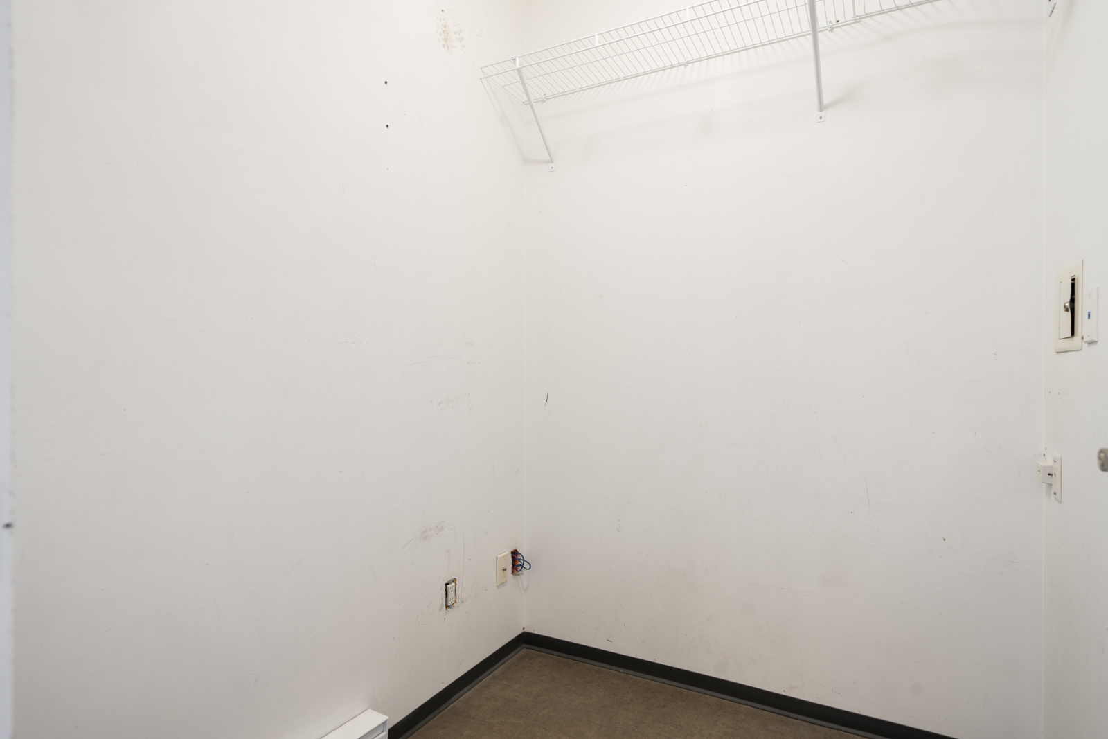 Empty white room with bare walls at 205 E 10th Ave, Vancouver; wire shelf near ceiling, utility outlets on one wall, 4th floor.