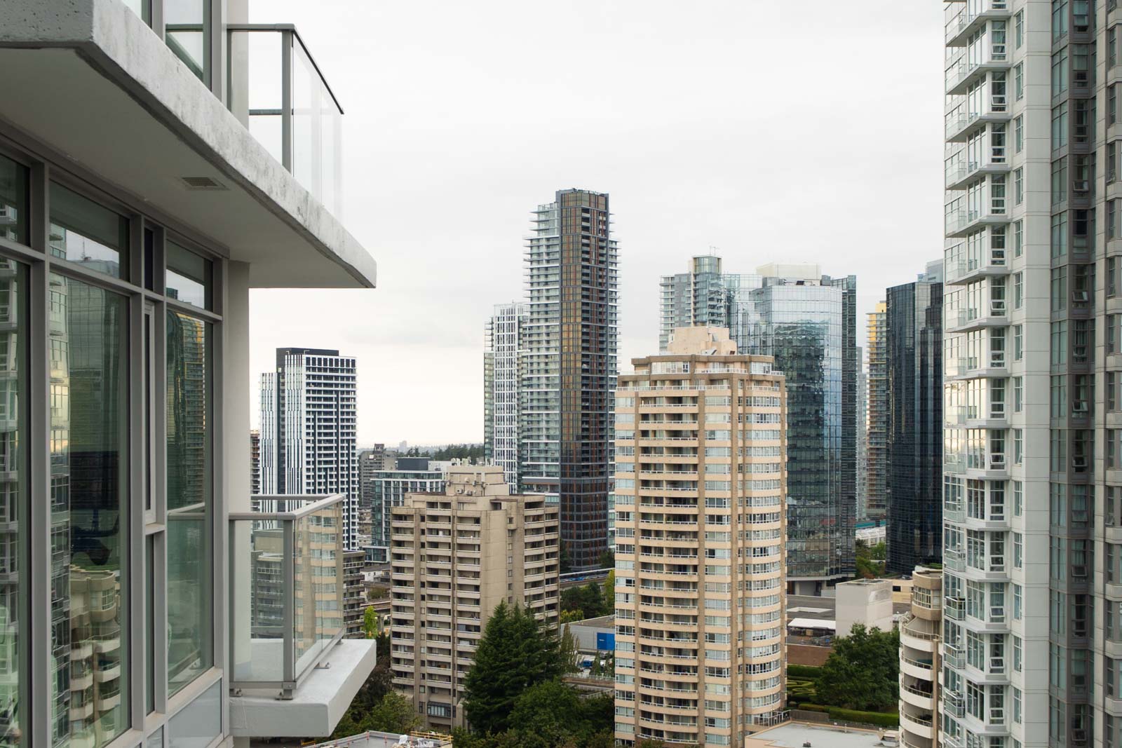 Cityscape view from the 27th floor on Nelson Ave, Burnaby—modern high-rises, cloudy sky, and street-level greenery.