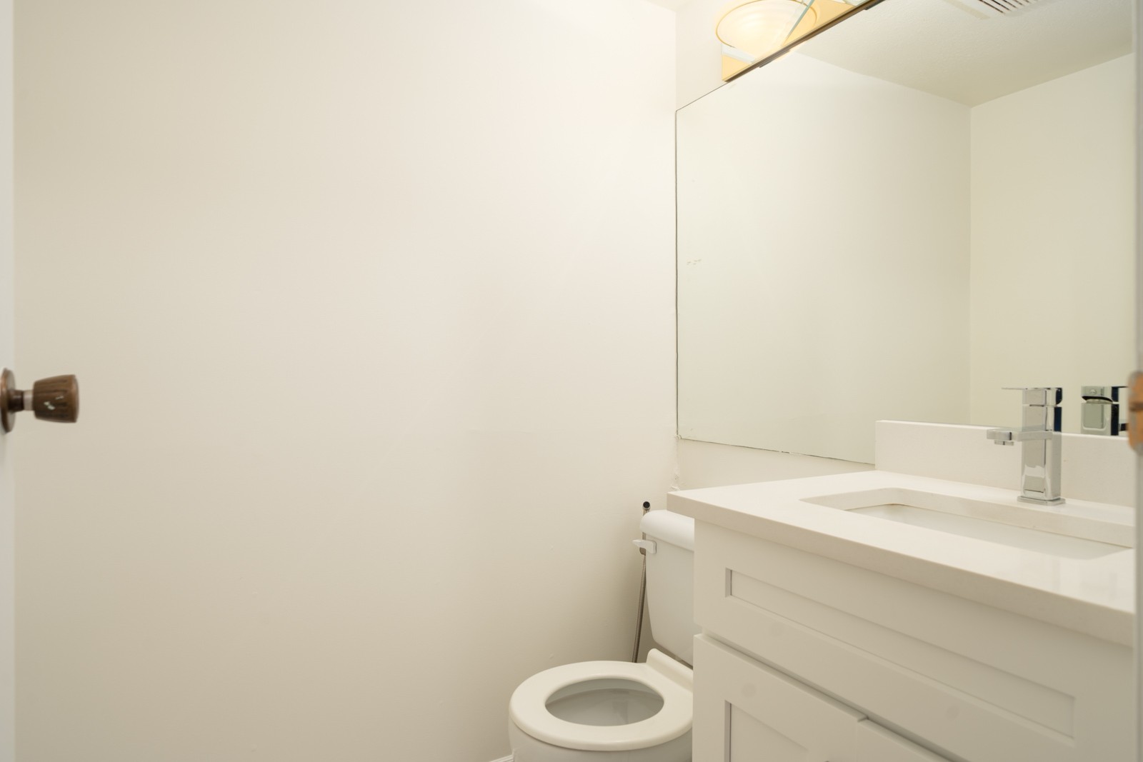 Small bathroom on 1st floor at 8460 Ackroyd Rd, Richmond with white walls, toilet, white vanity sink, mirror, and overhead light.