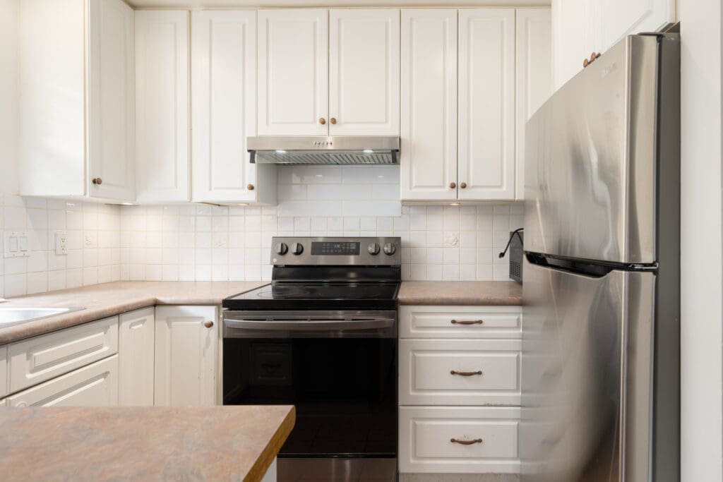 Modern kitchen on the 1st floor at 8460 Ackroyd Rd, Richmond with white cabinets, stainless fridge, and tiled backsplash.