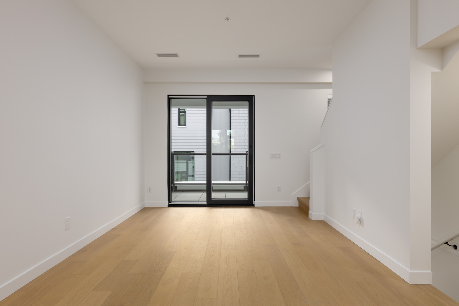 Empty room at 5433 Oak Street featuring light wood floors, white walls, and a sliding glass door leading to a balcony.