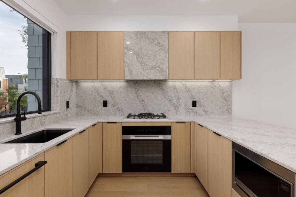 Modern kitchen at 5433 Oak Street with light wood cabinets, white quartz countertops, a gas cooktop, and a black sink.
