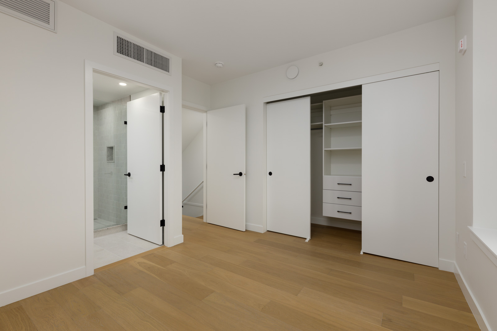 Hallway at 5433 Oak Street featuring light wood floors, an open bathroom door, and a walk-in closet with sliding doors.