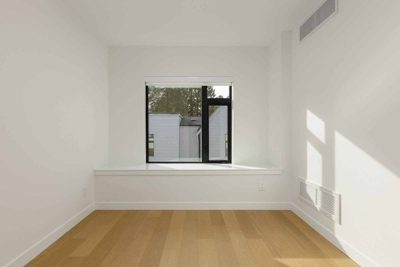 Empty room at 5433 Oak Street with white walls, light wood flooring, and a window looking out at neighboring houses.