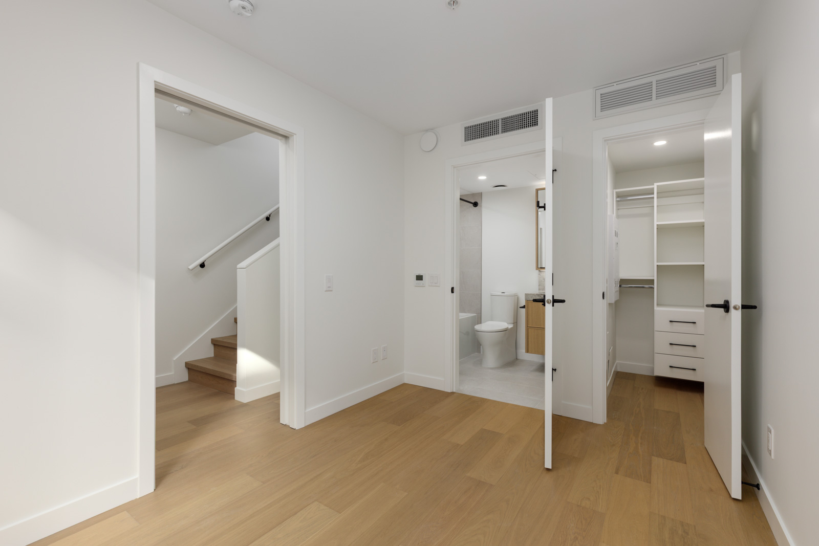 Hallway in a 5433 Oak Street townhouse with doorways leading to a staircase, a bathroom, and a walk-in closet.